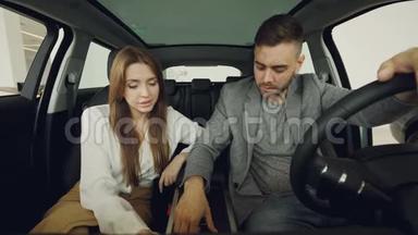 潜在的购车者夫妻两人正坐在前排座位上检查汽车内部